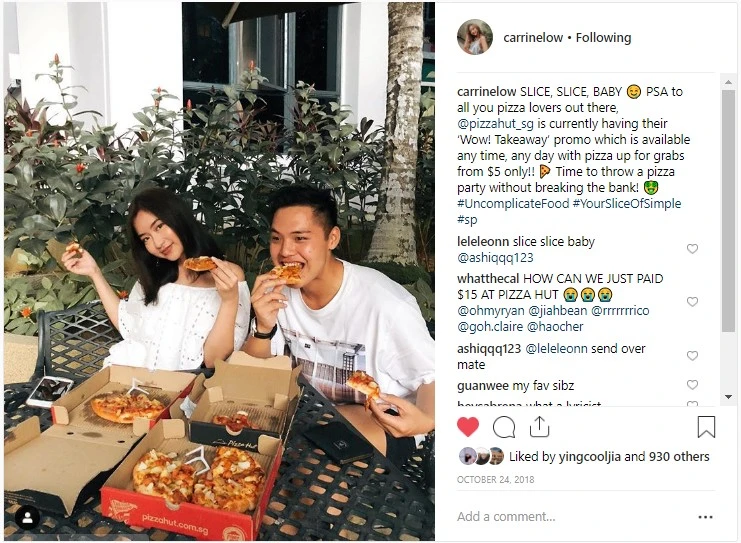 A young man and woman sit outdoors at a table, smiling and eating pizza from open Pizza Hut boxes, with a social media caption promoting a takeaway pizza deal.